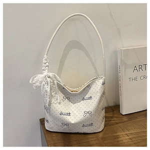 Dettaglio della borsa a tracolla bianca a pois con fiocco in pizzo e scritta sweet