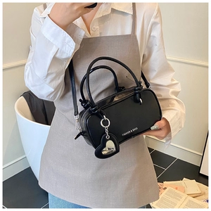 Vue latérale détaillée d'un sac cylindrique noir avec chaîne cœur et lettrage mode