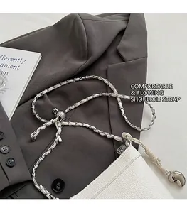 Détail de la texture cuir litchi blanc avec boucle en métal et bandoulière tressée