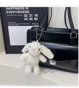 Gros plan d'un pendentif lapin en peluche blanche avec chaîne sur un cartable noir