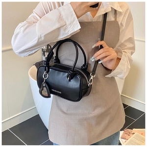 Sac à main cylindrique noir tendance avec breloque cœur présenté en situation
