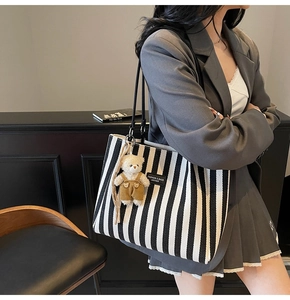 Détail du grand sac cabas à rayures avec lanières en cuir et breloque petit ours