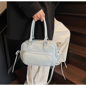 Detail of light blue lychee pattern leather handbag with ribbon bows and silver hardware