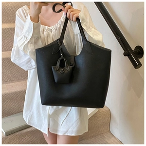 Detail of black large-capacity tote bag with matching mini pendant charm for women