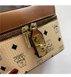 Detail of the golden dual-zipper and textured leather with cute cartoon bear pattern
