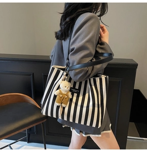 Sac fourre-tout en toile rayée noir et blanc avec lanières en cuir porté à l'épaule