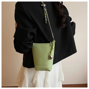 Détail du mini sac seau en cuir vert clair avec chaîne argentée et breloque cœur