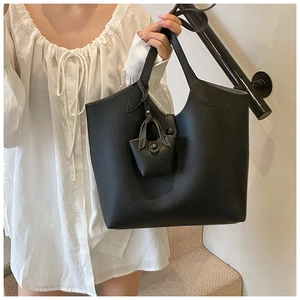 Close-up of black lychee grain leather tote bag with matching mini bag charm detail