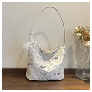 Dettaglio borsa in tela bianca a pois neri, testo Sweet e fiocco in pizzo decorativo