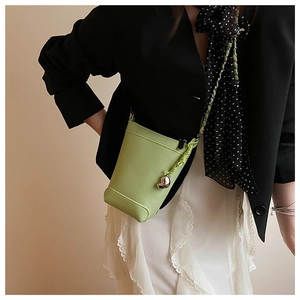 Détail du mini sac vert avocat texture litchi avec pendentif cœur et bandoulière chaîne