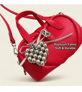 Détail du sac en cuir litchi rouge avec breloque cœur argentée et boucle métallique
