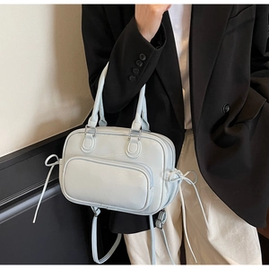 Detail of light blue crossbody bag with bow decoration and silver metal hardware