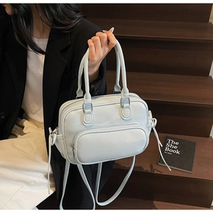Detail of light blue glossy leather handbag with zipper pocket on wooden steps