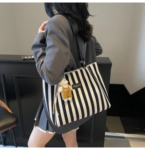 Détail du cabas en toile rayée avec anses en cuir et un charmant petit ours en peluche