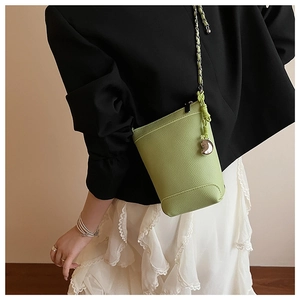 Gros plan du sac seau vert avocat en cuir grainé avec chaîne argentée et breloque cœur