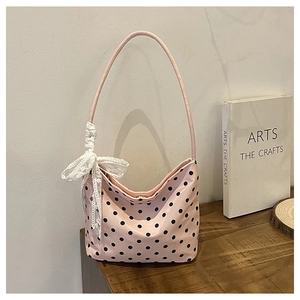 Dettaglio della borsa a spalla rosa a pois con delicato fiocco in pizzo bianco