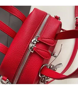 Gros plan des doubles fermetures éclair argentées sur le sac en cuir rouge grainé