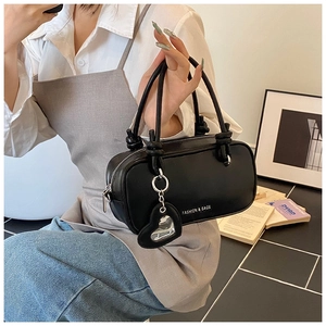Détail du sac polochon en cuir noir avec fermeture éclair argentée et breloque cœur
