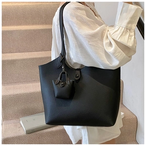 Close-up of black lychee-textured leather tote bag with matching mini pouch accessory