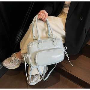 Detail of mint blue patent leather handbag with side drawstring bows on wooden stairs