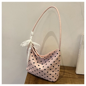 Dettaglio borsa a spalla rosa a pois con fiocco in pizzo bianco su tavolo in legno
