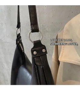 Detail of glossy black leather handbag with premium silver metal ring and rivet hardware