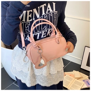 Sac cylindrique rose avec breloque miroir en cœur porté par un mannequin en décor de vie