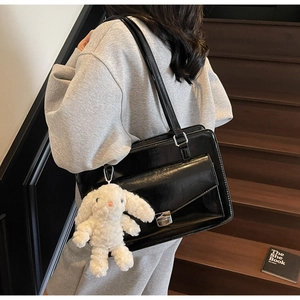 Détail d'un sac cabas en cuir noir brillant avec fermoir argenté et breloque lapin