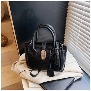 Detailed view of black pebbled leather texture and silver twist lock on bucket bag