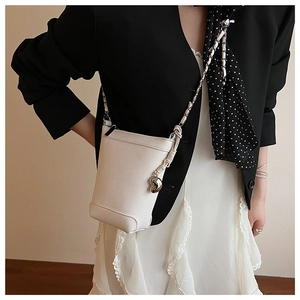 Détail du sac seau blanc en cuir avec pendentif cœur argenté et bandoulière en chaîne