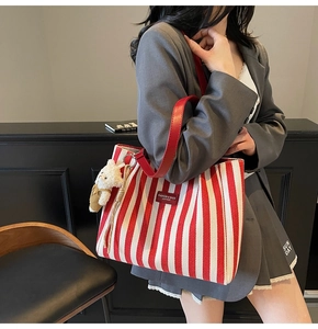 Détail du sac cabas à rayures rouges avec étiquette en cuir et porte-clé ourson