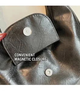 Detail of the magnetic buckle closure and high-quality black leather texture on the bag