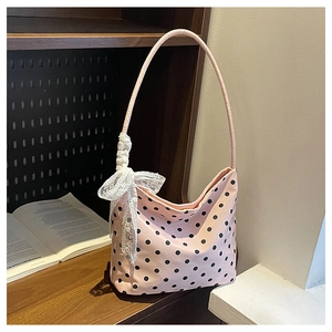 Dettaglio della borsa sottobraccio rosa a pois con fiocco in pizzo bianco sullo scaffale