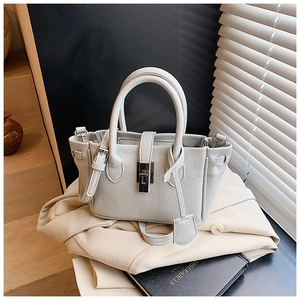 Detail of lychee pattern leather bucket bag with silver twist lock and shadow light