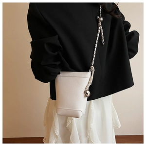 Détail du mini sac seau blanc avec texture litchi et pendentif cœur en métal