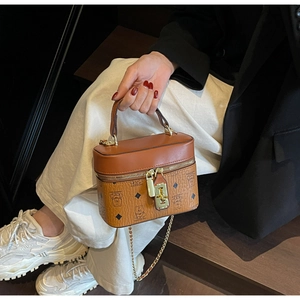 Detail of vintage brown monogram handbag with golden lock and chain strap carried by model