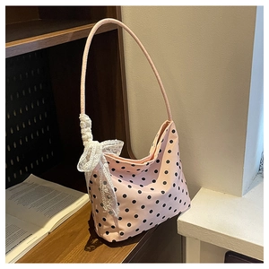 Dettaglio borsa rosa a pois con fiocco in pizzo bianco e forma a mezzaluna morbida