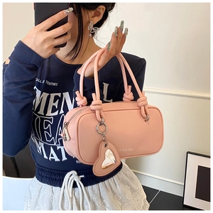 Détail du sac à main rose avec une poignée nouée unique et un accessoire en forme de cœur