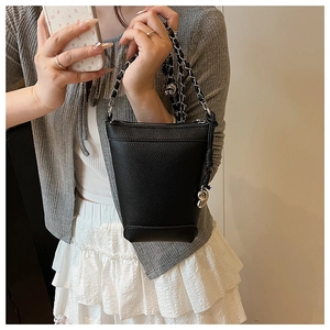 Vue détaillée du sac seau noir grainé avec bandoulière chaîne argentée et bijou ours