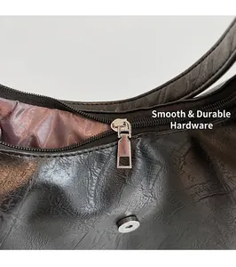 Close-up of the smooth silver zipper and embossed leather texture of the black hobo bag