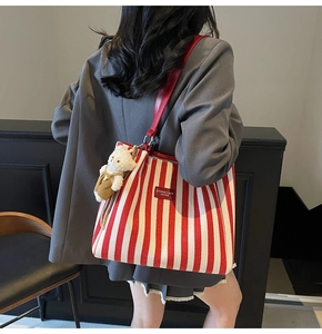 Détail du sac cabas en toile à rayures rouges et blanches avec charme d'ours