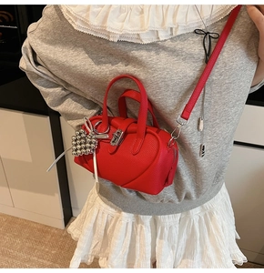 Détail d'un sac oreiller en cuir litchi rouge avec couture cœur et pendentif argenté