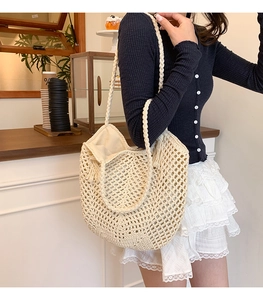 Detail of hollow woven tote bag with tassel charm worn by model in a cafe setting