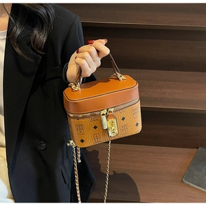 Close-up of caramel brown bucket bag with bear patterns and gold chain on wooden stairs