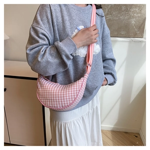 Detail view of pink and white checkered crescent crossbody bag on a female model