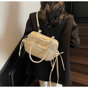 Close-up of beige lychee leather bag with multi-pocket design on wooden stairs