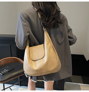Detail of vintage khaki hobo bag in lychee texture leather worn over the shoulder