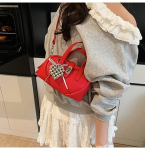 Détail du sac à main en cuir grainé rouge avec fermoir argenté et accessoires décoratifs