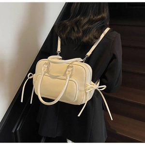 Detail of beige lychee textured women backpack showing side bow tassels and multi-pocket design