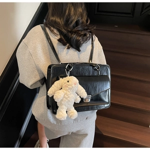 Détail du sac de messager noir brillant avec breloque lapin en peluche et boucle métal